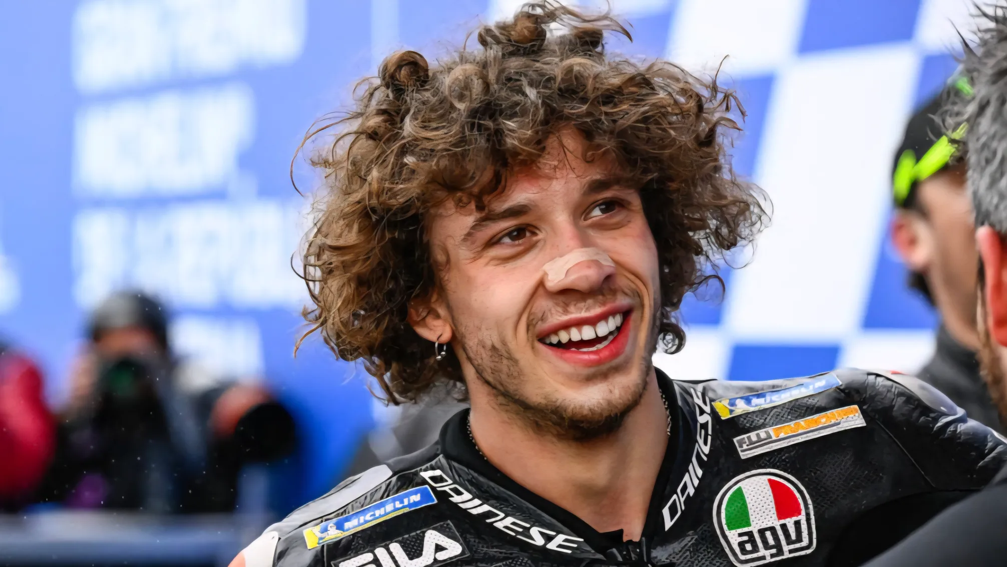 Marco Bezzecchi közelről mosolyog a verseny után, az Aprilia Racing MotoGP-pilótája a paddockban.