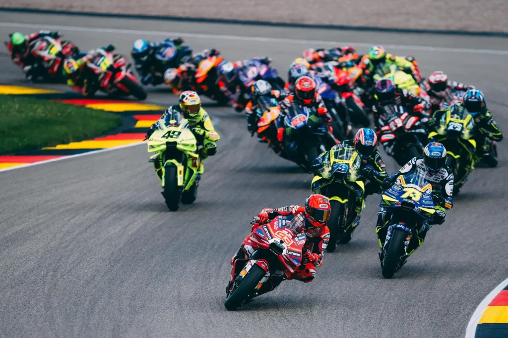 MotoGP közvetítés: DAZN kapta meg újra a MotoGP közvetítési jogot. A képen egy MotoGP közvetítés látható ahogy egy szűk kanyarban megy a MotoGP mezőny Marc Marquez az élen.
