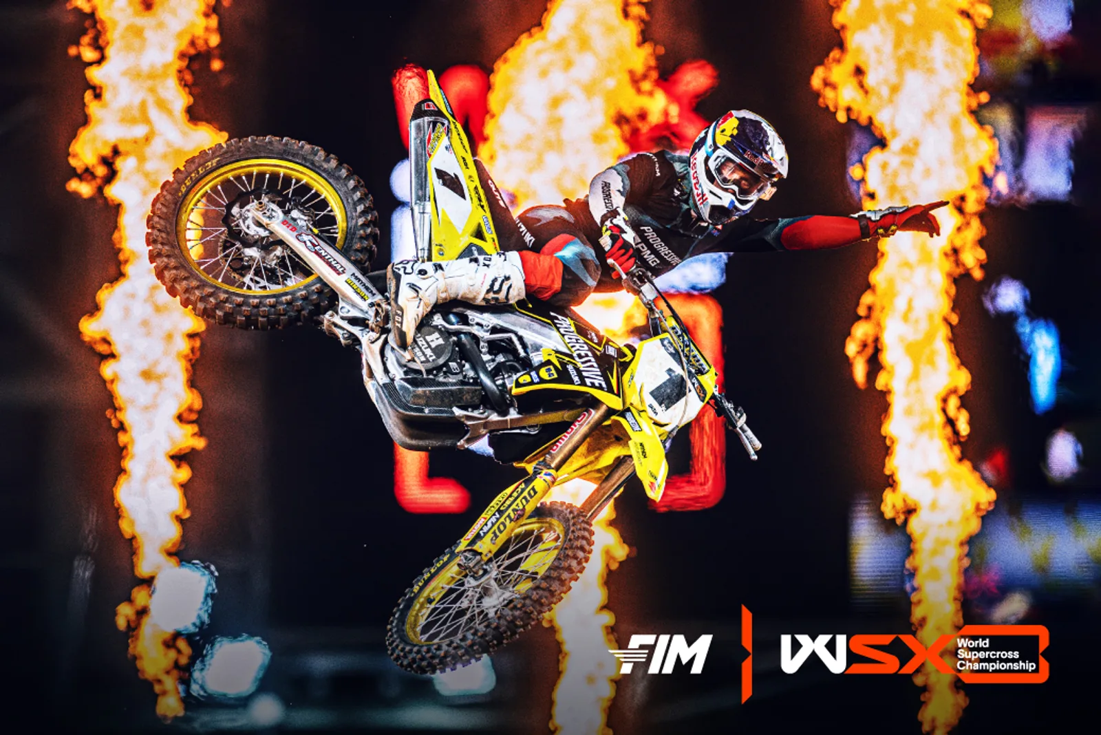 World Supercross versenyző ugrás közben, tűzoszlopok előtt