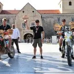 Thury vár előtt a rajt ceremónián 3 motorversenyző szemben áll velünk